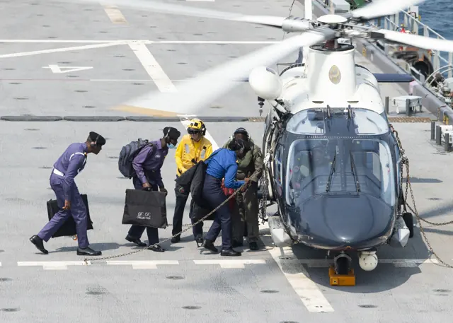 Sailors assigned to Air Department escort Nigerian Navy embarked officers to a Nigerian Navy AgustaWestland AW109 helicopter before taking off from the flight deck of USS Hershel "Woody" Williams (ESB-4) on 10 August 2021.