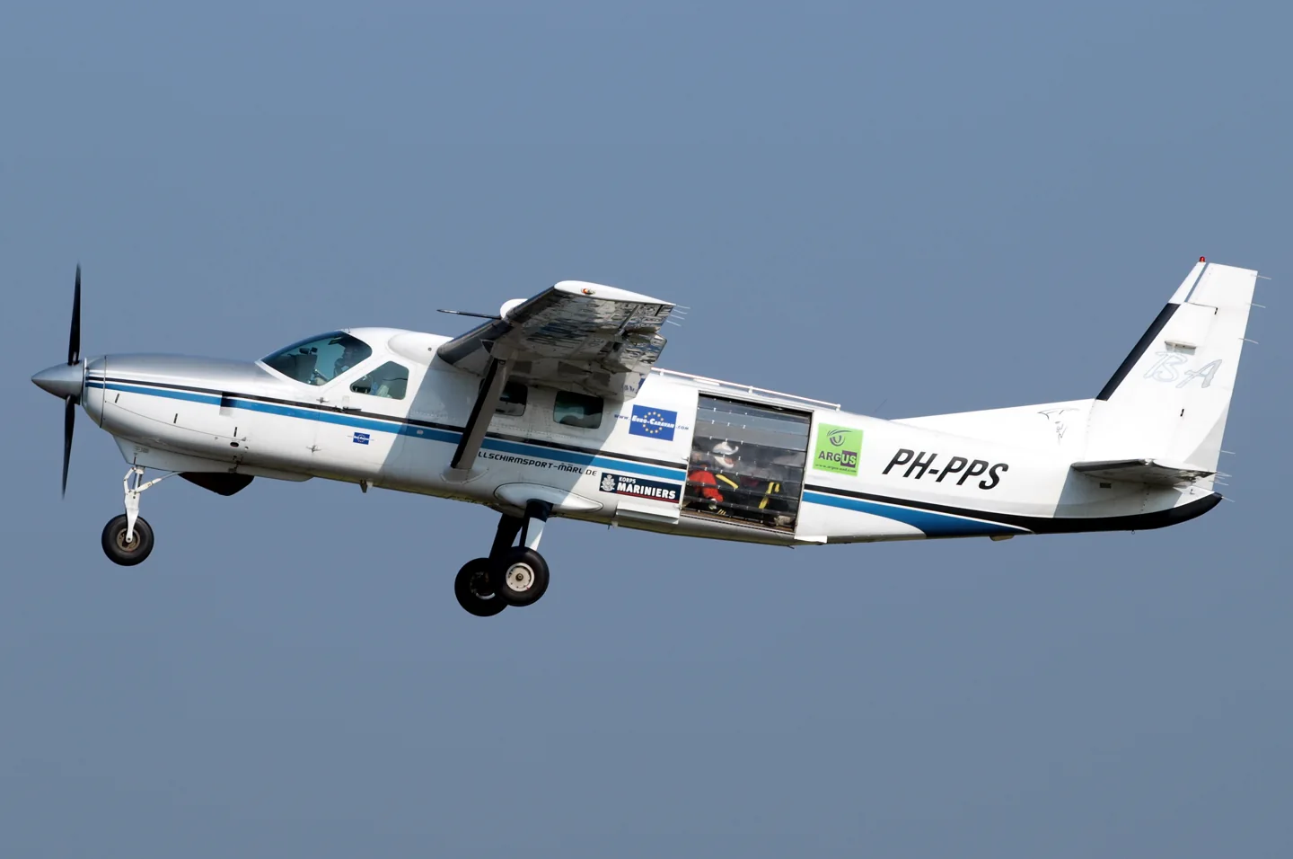 208B Grand Caravan in the Netherlands, modified with roller door for parachuting operations; skydivers sitting on the cabin floor are visible inside the rear roller door