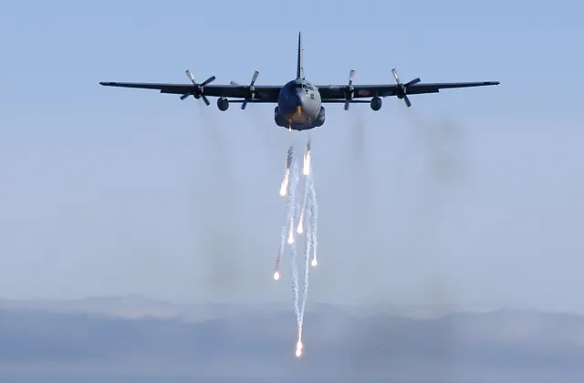 A Michigan Air National Guard C-130E dispatches its flares during a low-level training mission.
